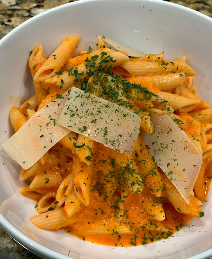 roasted red pepper sauce and penne pasta in bowl with cheese.